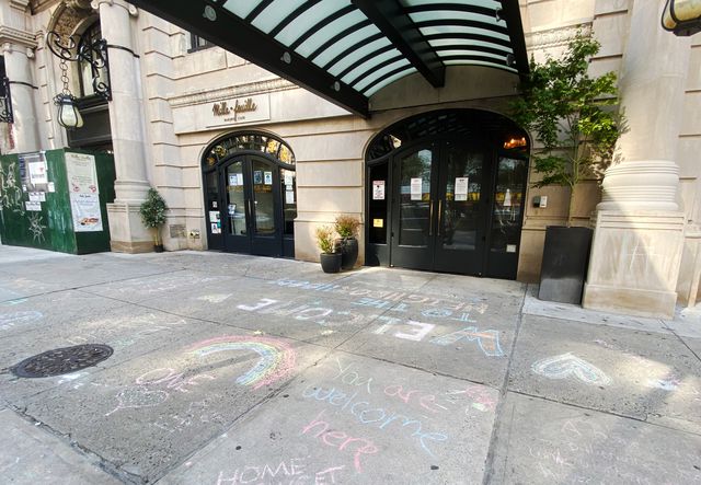 Chalk drawings and phrases like "Welcome to the Neighborhood" and "You Are Welcome Here" are on the sidewalk